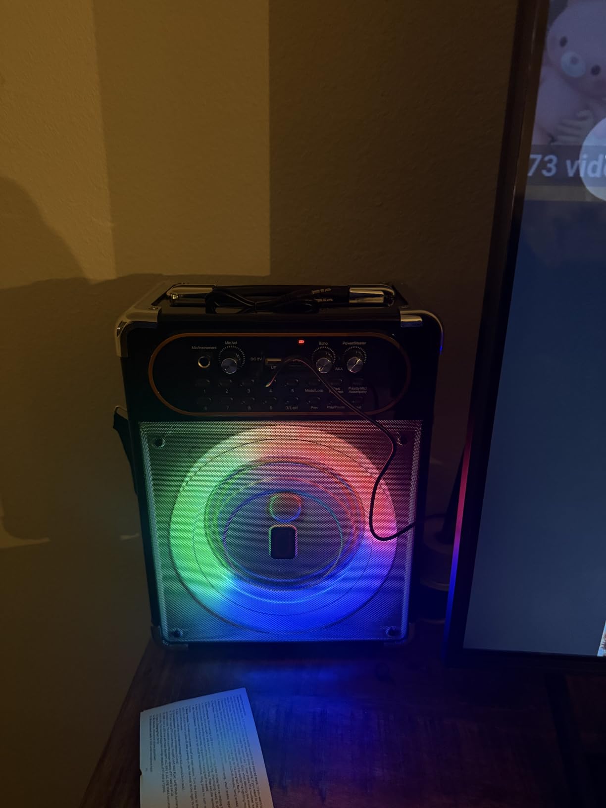 HWWR karaoke machine glowing with rainbow ring lights in a dark room next to a TV
