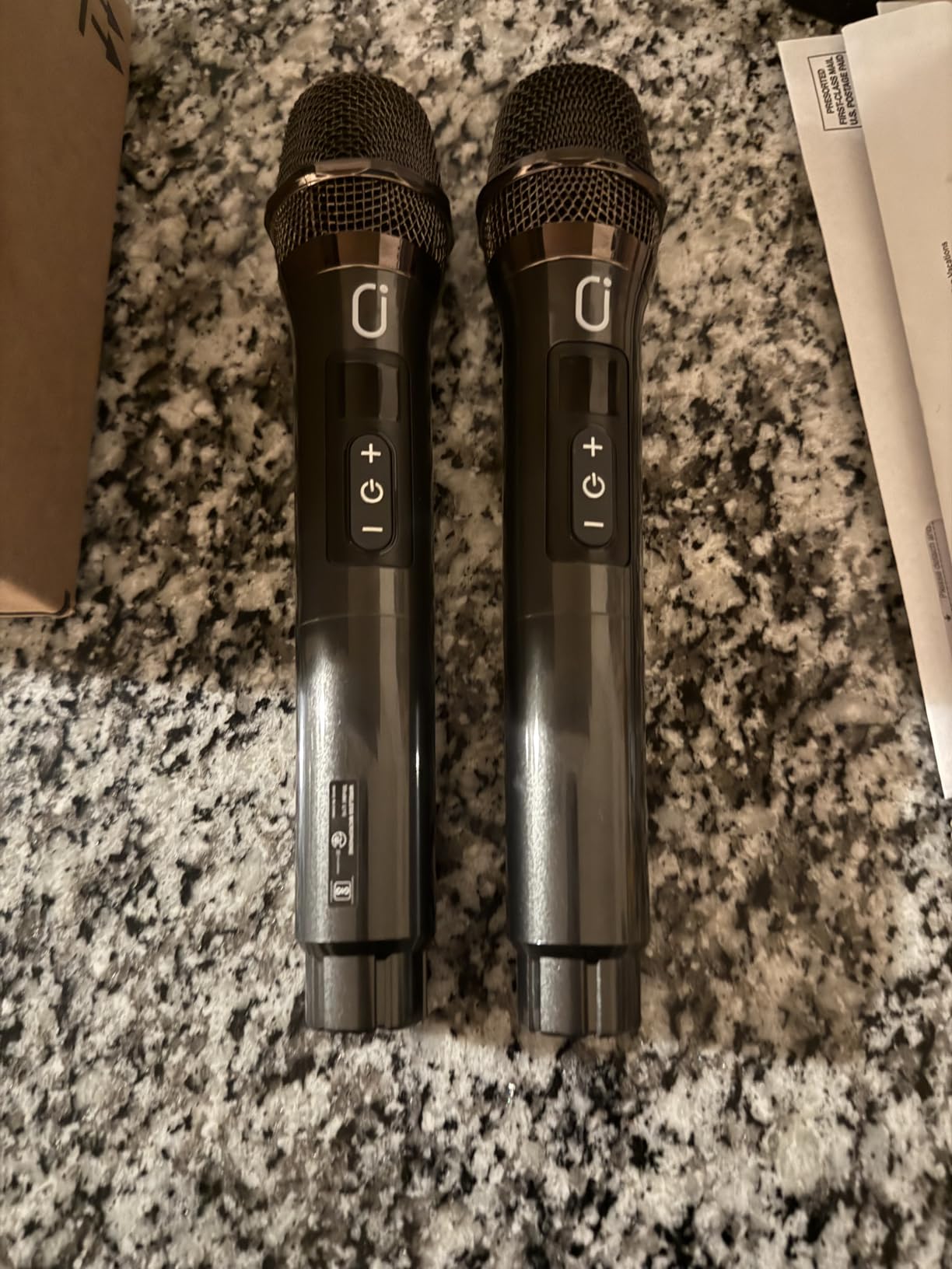 Two HWWR wireless microphones lying side by side on a granite countertop