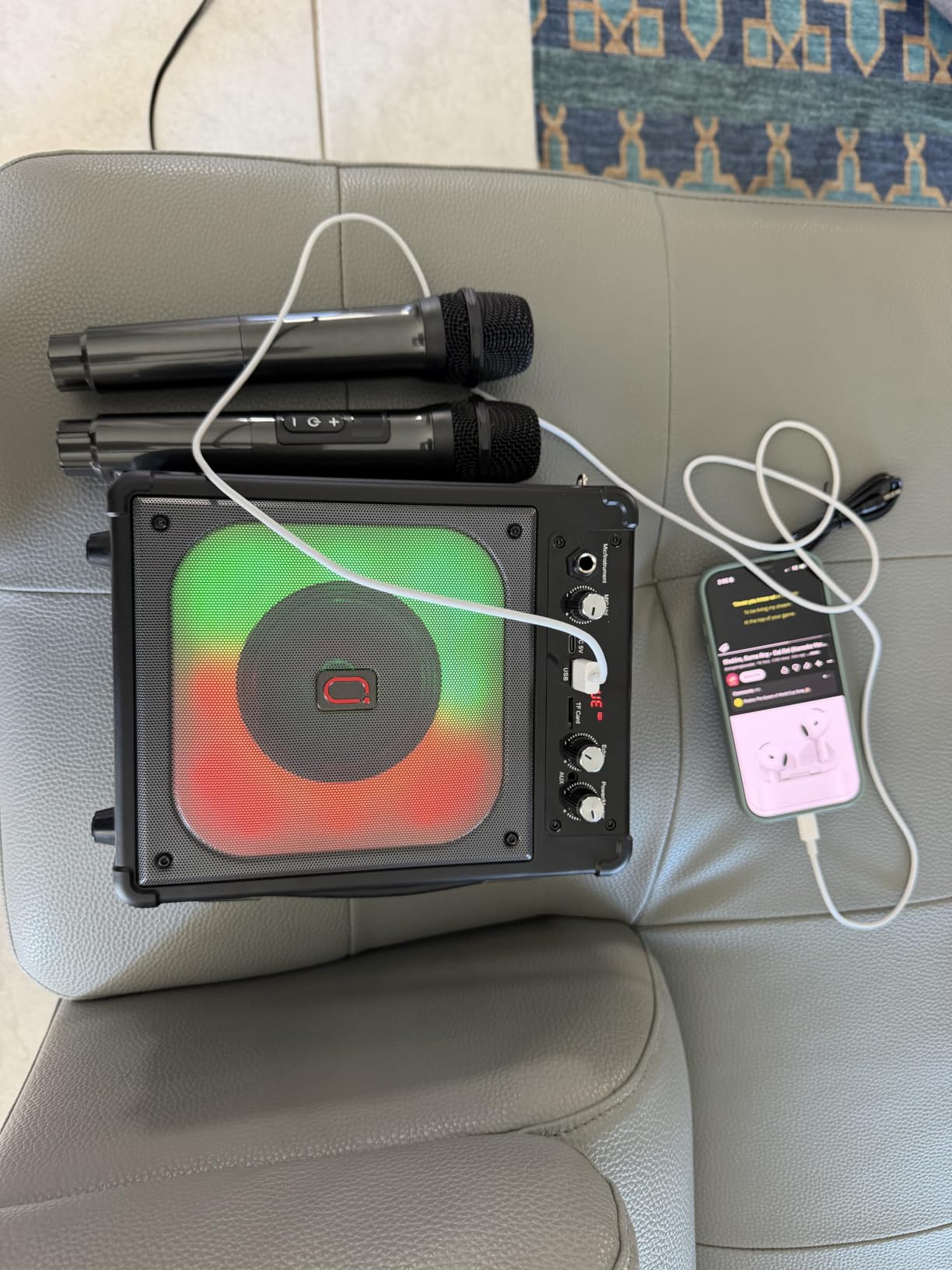 HWWR karaoke machine on a couch with two microphones on top and a phone connected by cable